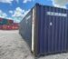 A professional delivery of a 20ft one-trip shipping container being placed on a level gravel foundation.